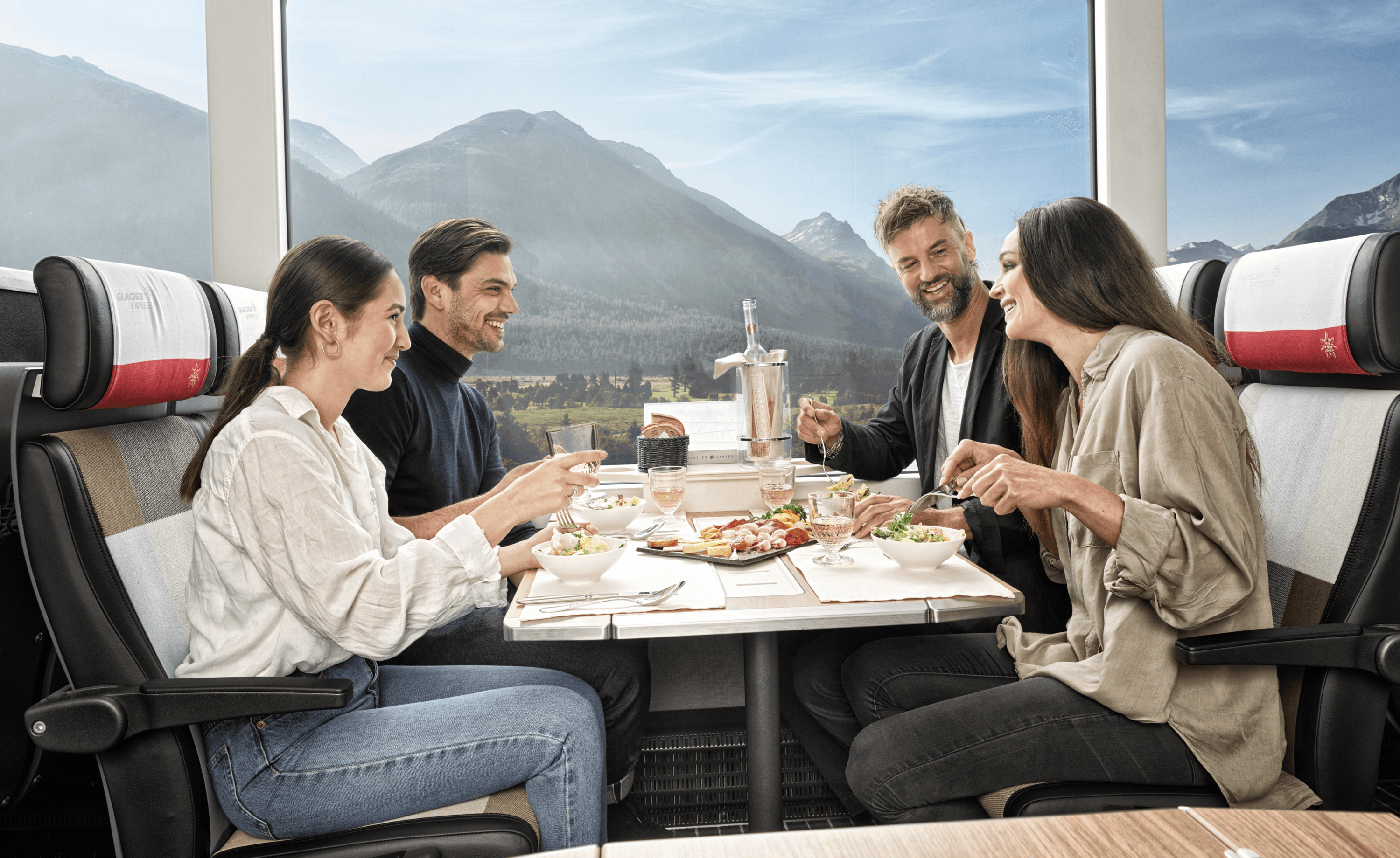 The image shows passengers dining together in the Glacier Express train while enjoying mountain views