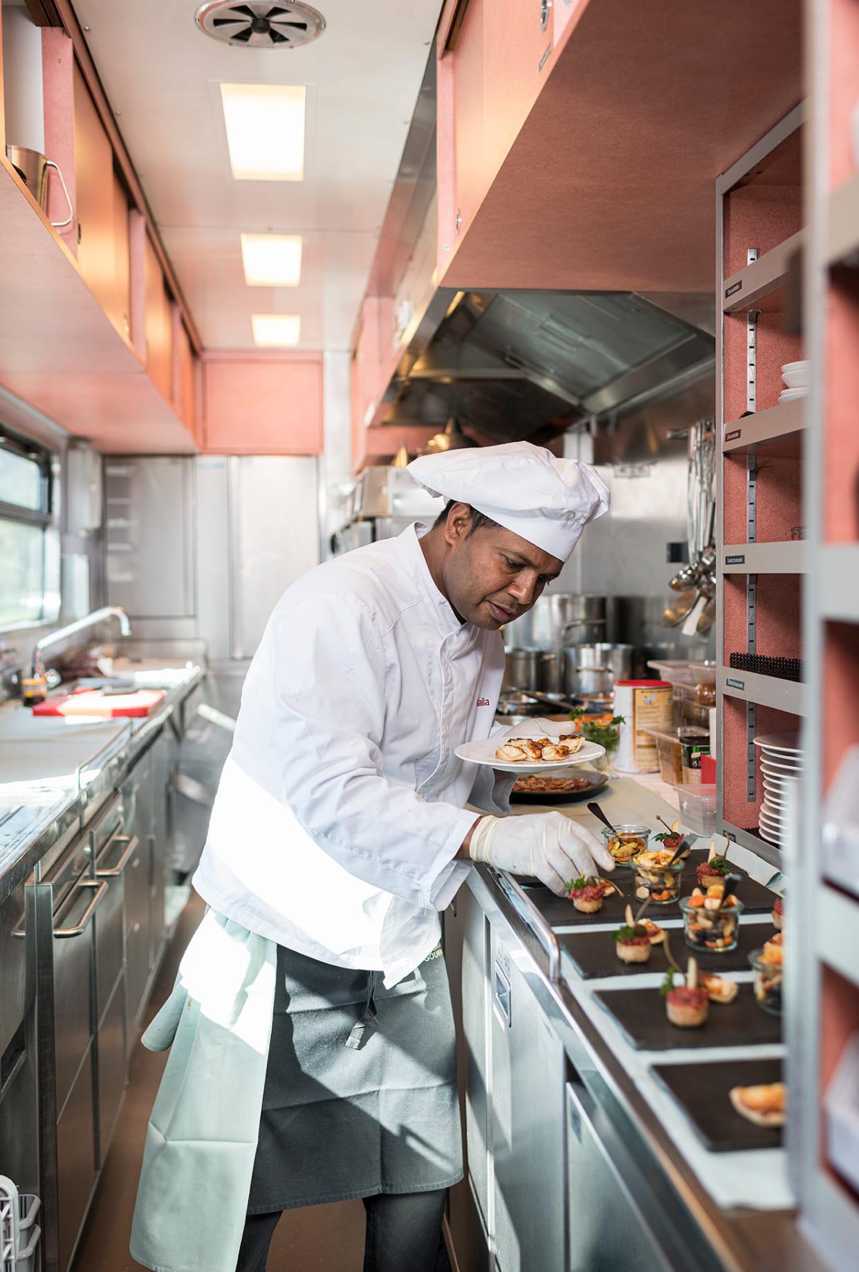 The image shows a chef preparing and plating dishes in a professional kitchen